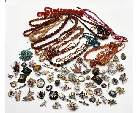 A collection of vintage costume jewellery including a number of beads, amber coloured necklaces and various brooches 