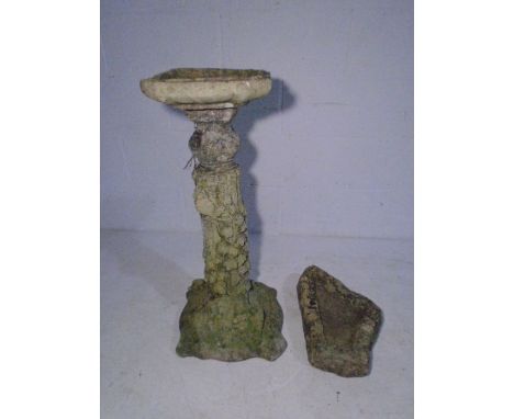 A weathered reconstituted stone birdbath along with a shallow trough.