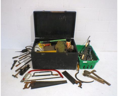A large black painted wooden trunk containing a large quantity of various tools including saws, hammers, files, axes etc.