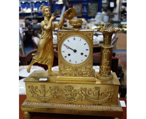 A FRENCH GILT METAL MANTEL CLOCK decorated with a figure, trophies in relief with enamel dial and striking on a bell, 36cm hi