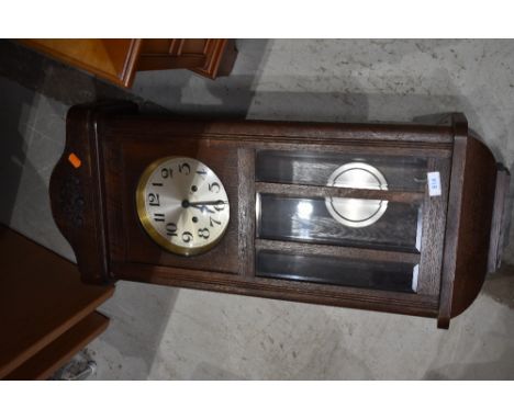 An Edwardian style oak cased wall mounted clock with polished dial