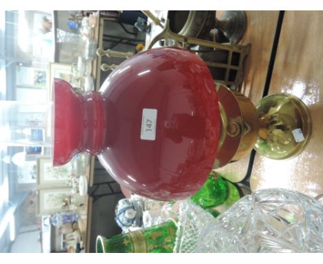 A brass oil lamp with red glass shade