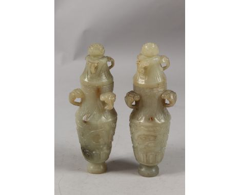 A PAIR OF CHINESE CARVED JADE LIDDED VASES, each with three ring handles to the neck and carved with archaic designs, 19cm hi