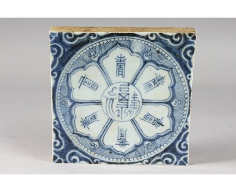 A CHINESE BLUE AND WHITE GLAZED POTTERY TILE, with symbolic flower motif and characters, 19cm square.