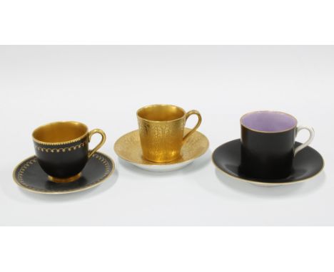 Two Royal worcester black glazed demitasse cups and saucers together with a Royal Doulton gilt glazed coffee can and saucer (