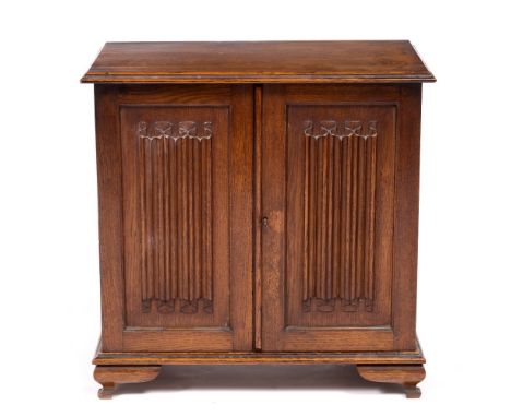 AN OAK TABLE CABINET with a pair of linen fold carved panelled doors, on ogee bracket feet, 46.5cm