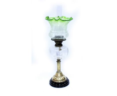 A LATE VICTORIAN OIL LAMP with clear glass reservoir and etched green tinted shade, robust mounts standing on black lacquered