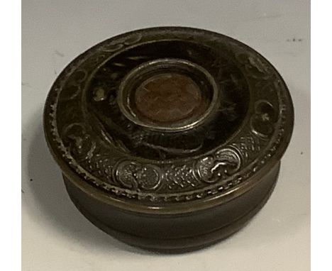 An 18th century pressed horn waisted circular snuff box, in relief with a basket of flowers, C-scrolls and trellis, the push-