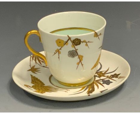 A Royal Worcester Aesthetic Movement cabinet cup and saucer, decorated in gilt and silver with stork, bamboo and blossoming b