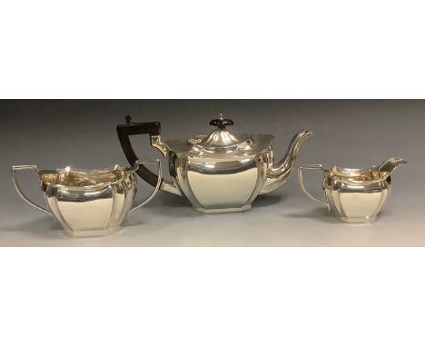 A silver three piece panelled boat shaped tea service, ebonised button final, angular handle, William Aitken, Birmingham 1927