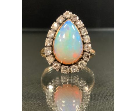 An opal and diamond ring, large pear cabochon opal, flashing vibrant green, blue and violet colour play, measuring approx 15m