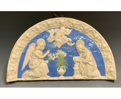 A Della Robbia style semi-circular plaque,  moulded in high relief with the Annunciation, within a border of cherub heads and