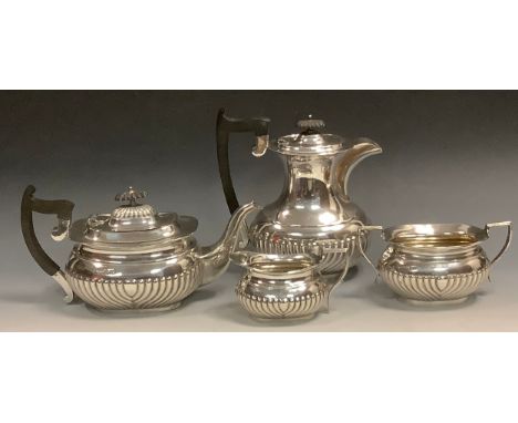 A silver half fluted boat shaped three piece tea service, comprising teapot,  milk jug and sugar bowl, ebonised finials and h