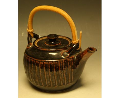 A salt glazed stoneware teapot, by Geoffrey Whiting, in shades of black and brown, cane handle, 18cm overall, impressed seal 