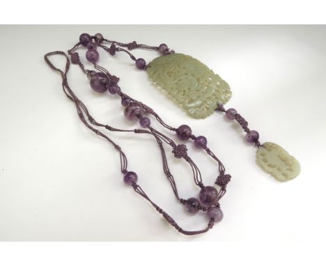 A jade carved and pierced panel depicting figures in foliage 7cm x 4cm on an amethyst bead and purple knotted necklace 