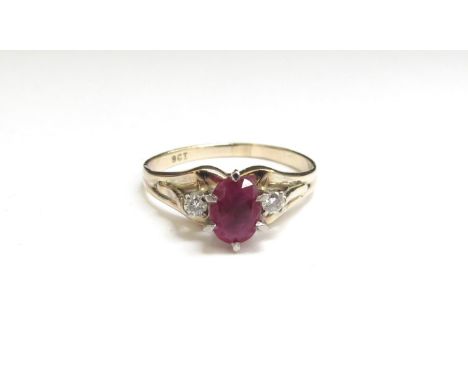 A gold ruby and diamond ring, the centre oval ruby flanked by diamonds, stamped 9ct. Size S, 3.2g 