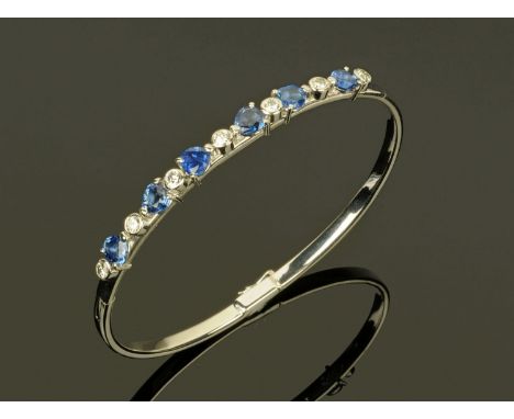An 18 ct gold sapphire and diamond set bangle, sapphire weight +/- 5.96 carats, diamonds +/- 1.05 carats (see illustration). 