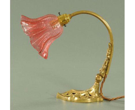 An Art Nouveau brass adjustable table lamp with cranberry glass shade, with applied and cast leaf and berry decoration.  Heig