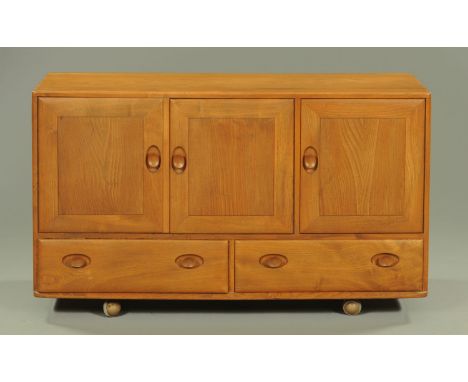 An Ercol light elm sideboard, circa 1960/70's, of rectangular form, with well figured top above three cupboard doors and two 