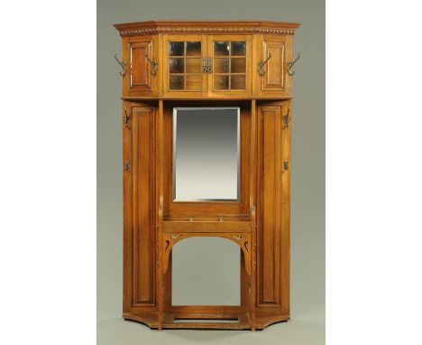 A good Arts & Crafts oak hall stand, with carved top above two cupboard doors each six moulded glass panes flanked by moulded