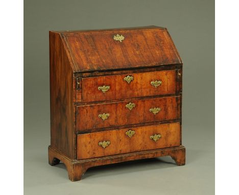 An early 18th century walnut bureau, with slope front to fitted interior and with three drawers with brass drop handles with 