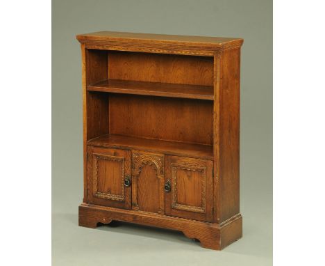 An oak open bookcase, with two shelves above cupboard doors and raised on bracket feet.  Width 84 cm. 