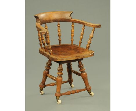 A 19th century smokers bow style swivel office chair, with turned spindles and legs resting upon brass and ceramic castors.  