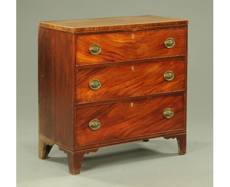 A George III mahogany chest of three long graduated drawers, with brass drop handles with oval backplates and raised on brack