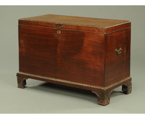 A George III mahogany blanket box, having a carved border and base, with side carrying handles, all supported upon carved bra