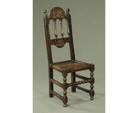 An early 18th century dark oak side chair, having an arched top rail with carved floral decoration above an arcaded back with