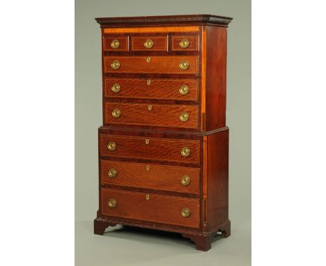 A George III mahogany satinwood banded chest on chest, with moulded dentil cornice above a series of drawers with brass drop 