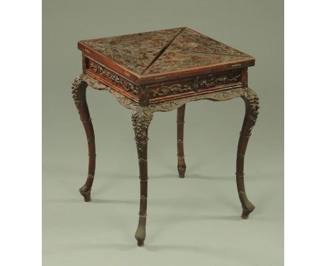 A Chinese carved rosewood envelope card table, late 19th century, the top carved with dragons with sacred pearl amongst cloud