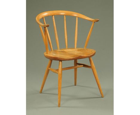 An Ercol light elm armchair, mid 20th century, with horseshoe shape back rest supported on spindles and with dished seat on t