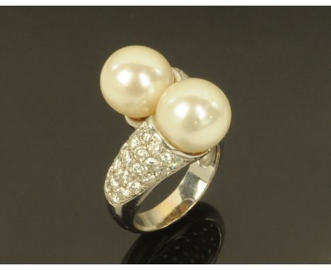 A pearl and diamond crossover ring, with two large pearls and diamond set shoulder on a white metal shank, size K/L (see illu