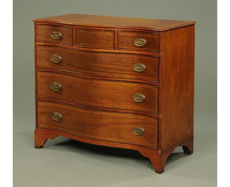 A George III mahogany serpentine fronted chest of drawers, with strung drawer fronts and with brass drop handles with oval ba