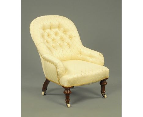 A Victorian button back nursing chair, upholstered in a cream lozenge patterned material and supported upon turned front legs