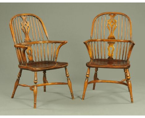 A pair of comb back Windsor armchairs, each with pierced central splat above a dished seat supported upon turned legs united 