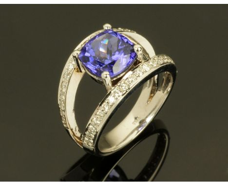 An 18 ct white gold ring with cushion cut tanzanite to diamond set split shank, total weight +/- 3.1 carats (see illustration