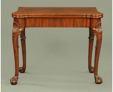 An 18th century red walnut card table, the top opening to reveal a baize surface with circular corners and wells, resting upo