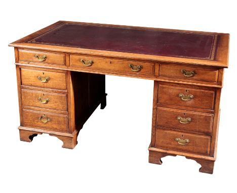 AN EDWARDIAN OAK PEDESTAL DESKthe rectangular top inset with a gilt tooled leather writing surface over an arrangement of nin