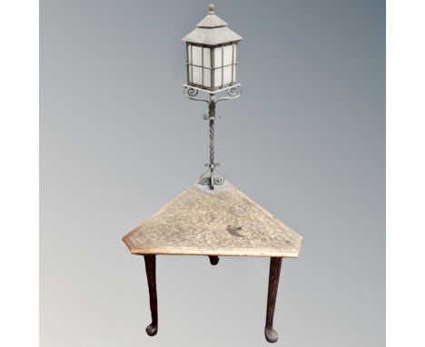 A carved poker work triangular table fitted with a lamp 