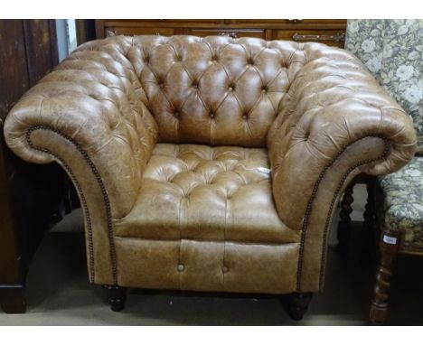 A brown leather button-back upholstered Chesterfield armchair 