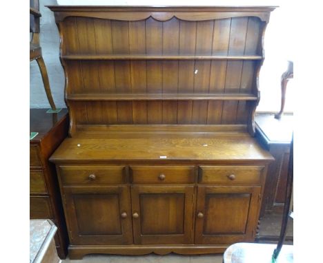 A dark Ercol dresser, with a boarded open plate rack, and fitted drawers and cupboards under, bracket feet, W134cm, H166cm 