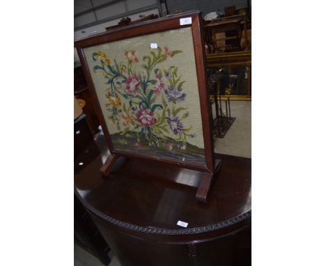 A tradirional mahogany framed woolwork firescreen