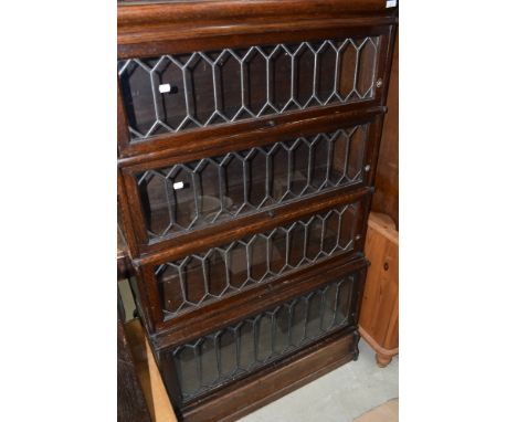 A late 19th or early 20th Century four tier oak stacking bookcase, having leaded glass fronts, labels removed but most likely