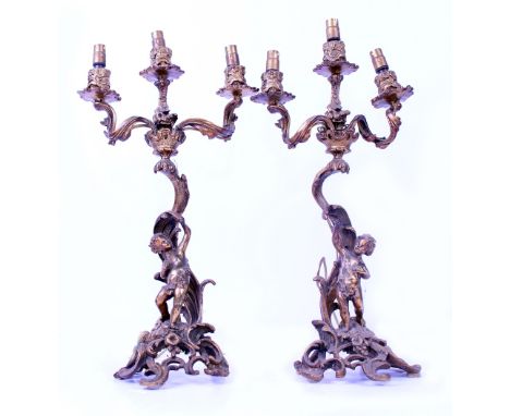 A PAIR OF GILT METAL THREE BRANCH CANDELABRA with Cherubs and scrolling acanthus leaf, converted to electricity, each 94cm in