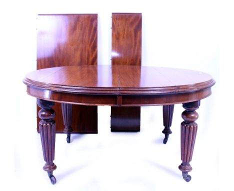 AN EARLY VICTORIAN MAHOGANY WIND OUT DINING TABLE with reeded legs terminating in brass and ceramic casters, the oval top wit