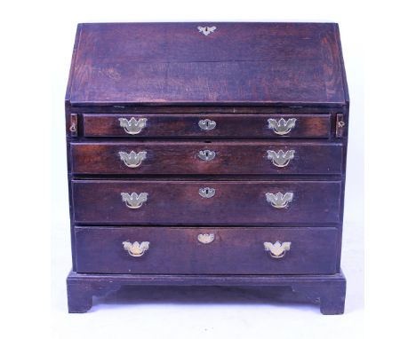 A GEORGIAN OAK BUREAU the fall front opening to reveal pigeon holes and drawers above four long graduated drawers with brass 