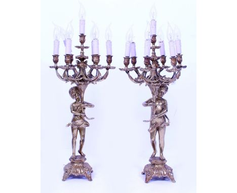 A PAIR OF GILT METAL SEVEN BRANCH CANDELABRA of cherub form with scrolling acanthus leaf branches, converted to electricity, 