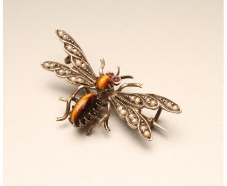 A NOVELTY MOTH BROOCH with polished tiger's eye body and head, ruby eyes and seed pearl set wings to an unmarked frame, 1 1/2